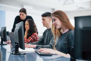 telas de computador. grupo de jovens em roupas casuais trabalhando no escritório moderno foto