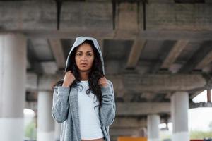 menina estilosa. retrato de mulher jovem e bonita em pé debaixo da ponte ao ar livre foto