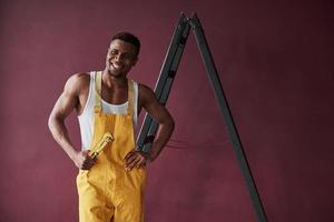 pessoa atraente. jovem trabalhador afro-americano de uniforme amarelo tem algum trabalho foto