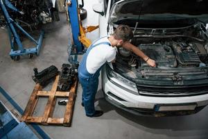 apenas alguns minutos. funcionário de uniforme de cor azul trabalha no salão de automóveis foto