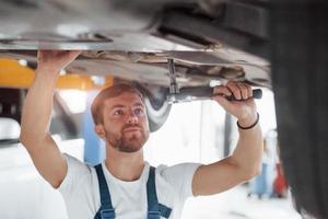 belo raio de sol. funcionário de uniforme de cor azul trabalha no salão de automóveis foto