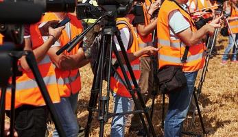 grupo de pessoas de uniforme amarelo e com câmeras fica ao ar livre no campo foto