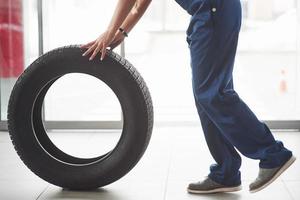 foto recortada. mulher caminha com roda nova para o carro. concepção de reparação