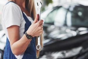 isso vai se encaixar bem. O reparador de boa mulher loira está em seu trabalho. dentro de casa na loja de carros foto