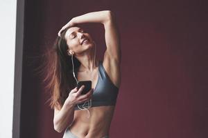 música é vida. garota com bom tipo de corpo fitness tem exercícios na sala espaçosa foto