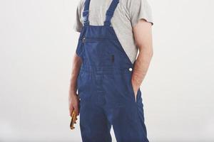 foto recortada. homem de uniforme azul fica contra um fundo branco no estúdio