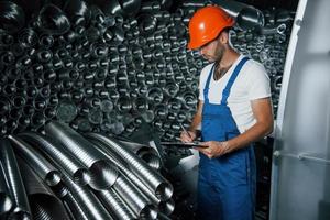 no armazenamento. homem de uniforme trabalha na produção. tecnologia industrial moderna foto