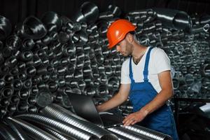 fica no depósito. homem de uniforme trabalha na produção. tecnologia industrial moderna foto