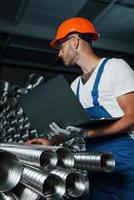 foto vertical. homem de uniforme trabalha na produção. tecnologia industrial moderna