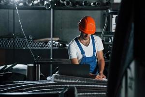 vista frontal. homem de uniforme trabalha na produção. tecnologia industrial moderna foto