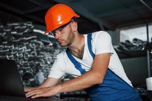 cara barbudo. homem de uniforme trabalha na produção. tecnologia industrial moderna foto