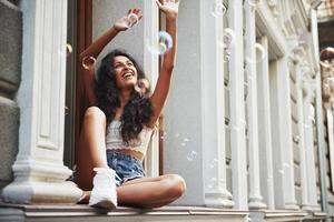 a felicidade está nas pequenas coisas. mulher bonita com cabelo preto encaracolado se diverte na cidade durante o dia foto