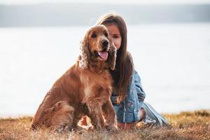 menina bonitinha passear com seu cachorro ao ar livre em dia ensolarado foto