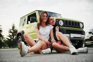 duas amigas se divertem sentando no novo veículo verde foto