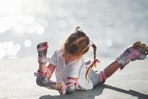 deitado. menina bonitinha com patins ao ar livre perto do lago no fundo foto