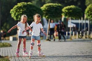 dois lindos filhos andando de patins no parque durante o dia foto