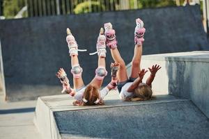 pernas para cima. Sentindo livre. na rampa para esportes radicais. duas meninas com patins ao ar livre se divertem foto