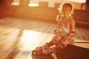 criança bonita feliz com seus patins. luz solar inacreditável foto