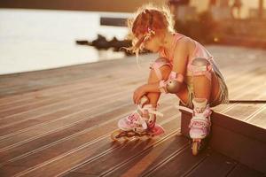 criança bonita feliz com seus patins. luz solar inacreditável foto