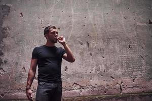 retrato de homem de camisa preta fumando no fundo da velha parede rachada foto