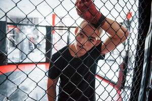 Tire uma folga. esportista no ringue de boxe tem exercício. encostado na cerca foto