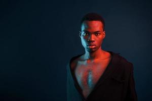 confiante e sério. iluminação neon futurista. jovem afro-americano no estúdio foto