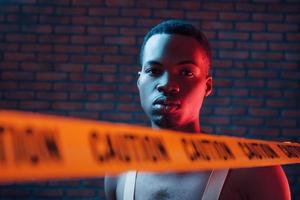 fita isolante amarela e uniforme. iluminação neon futurista. jovem afro-americano no estúdio foto