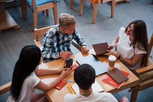 sentado no café e conversando. quatro jovens estudantes em roupas casuais se encontram em um dia chuvoso foto