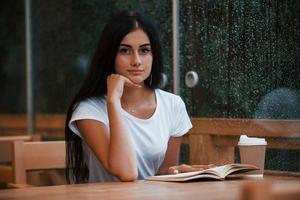 retrato de jovem aluna que se senta no café em dia chuvoso. uma pessoa só foto