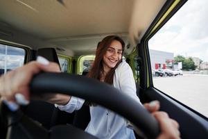 proprietário feliz. vista frontal da mulher que dirige carro novo moderno na cidade foto