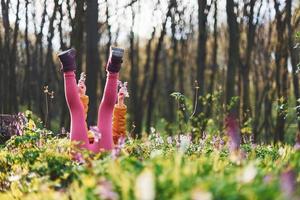 menina feliz em roupas casuais, deitado no chão na floresta de primavera durante o dia foto