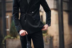 vista de perto. segurando guarda-chuva. jovem elegante em roupas elegantes formais ao ar livre na cidade foto