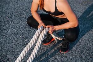 mulher em roupas esportivas sentada com nós na estrada ao entardecer foto