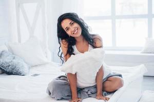 linda mulher. morena descansando no sofá branco em seu quarto durante o dia foto