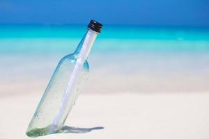 garrafa com uma mensagem na areia branca foto