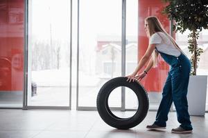 portas está se abrindo. mulher caminha com roda nova para o carro. concepção de reparação foto