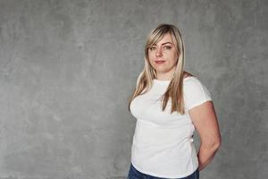 roupas casuais. jovem mulher branca no estúdio em pé contra um fundo cinza foto