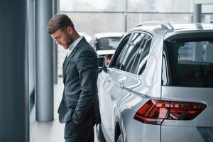 olhar pensativo. empresário barbudo elegante moderno no salão do automóvel foto