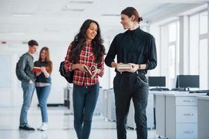 Eu tenho um bom plano. grupo de jovens andando no escritório na hora do intervalo foto