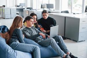 pressionando o botão entrar. grupo de jovens em roupas casuais trabalhando no escritório moderno foto