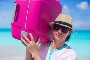 homem carregando bagagem na praia foto