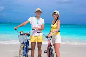 casal feliz com bicicletas em uma praia de areia branca foto