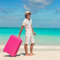 homem com bagagem na praia foto