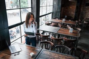 olhar preocupado. empresária em roupas oficiais está dentro de casa no café durante o dia foto