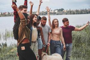 vista lateral. grupo de pessoas faz piquenique na praia. amigos se divertem no fim de semana foto