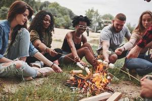 isso vai ser delicioso. grupo de pessoas faz piquenique na praia. amigos se divertem no fim de semana foto