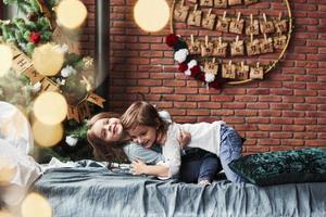 tão fofo. meninas se divertindo na cama com interior de férias ao fundo foto