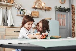 Infância feliz. duas crianças brincando com brinquedos amarelos e laranja na cozinha branca