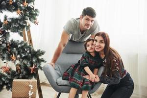 férias juntos. retrato da família feliz na celebração do ano novo. menina senta na cadeira foto