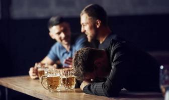 três amigos do sexo masculino no bar. apoiando amigo triste. unidade das pessoas. com cerveja na mesa foto